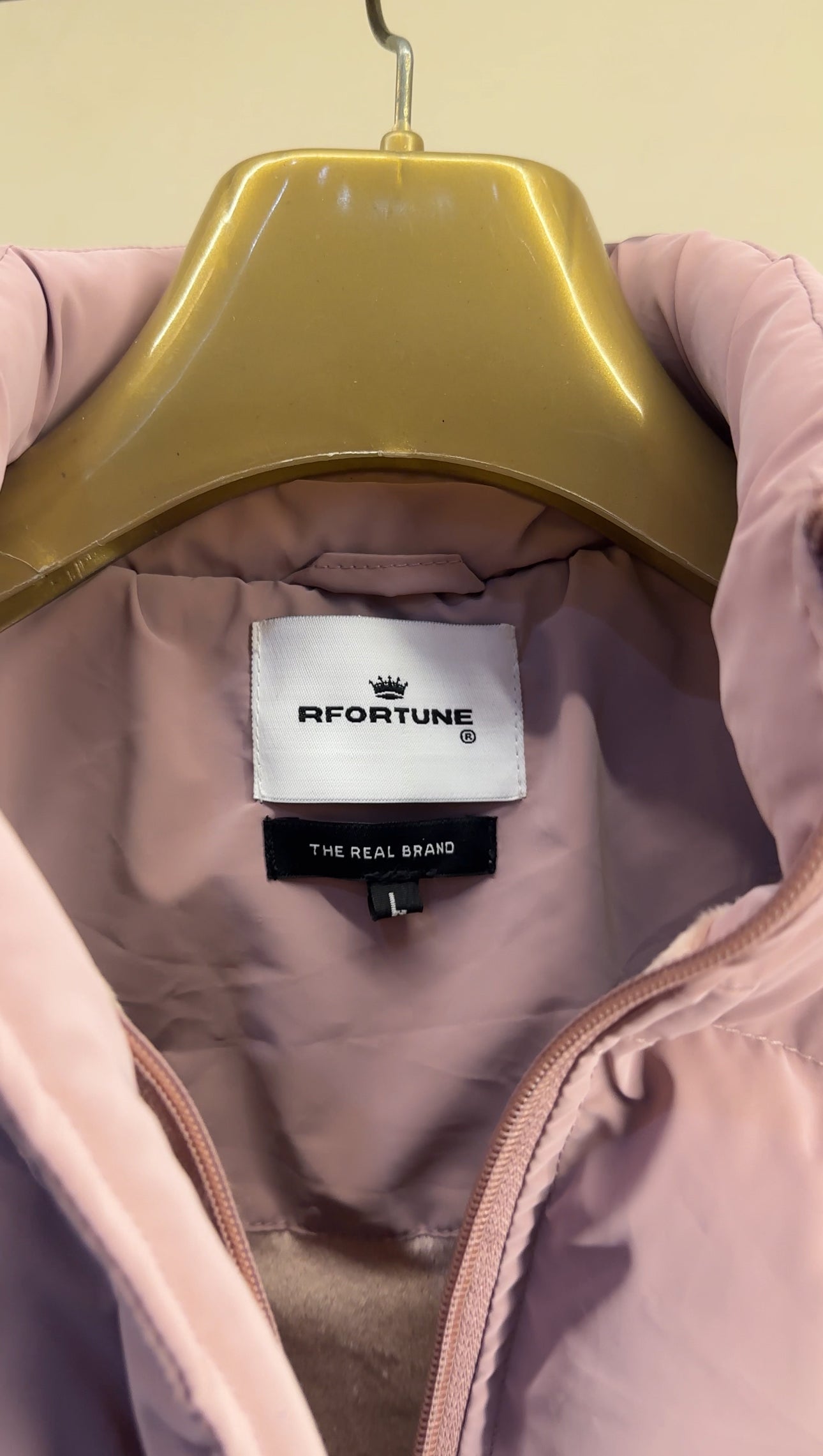 Inner collar view of a Puffer jacket women option in pastel pink, featuring a label with the brand name "RFORTUNE" and the tagline "THE REAL BRAND".