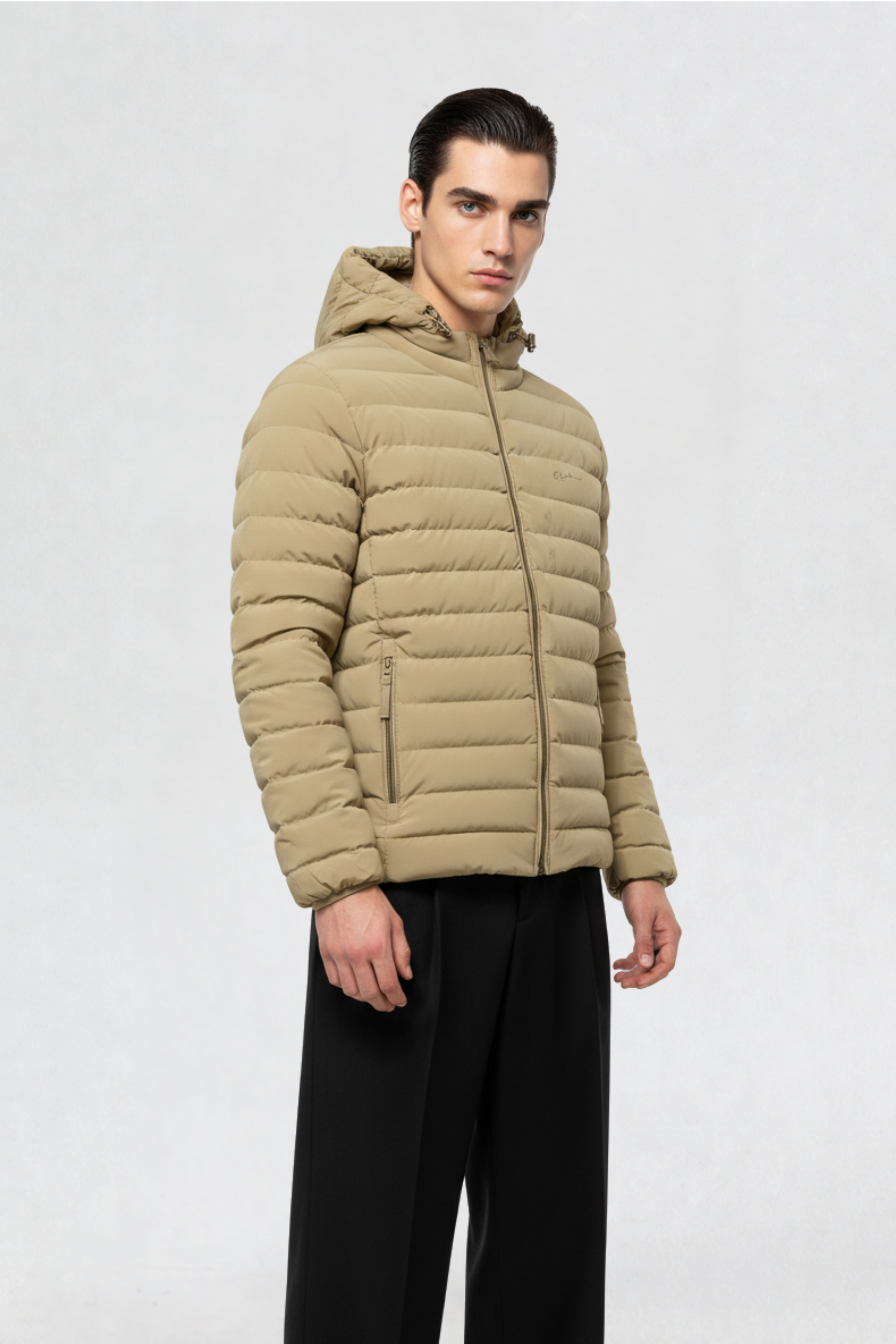 Side angle of male model wearing a beige mens puffer jacket with hood