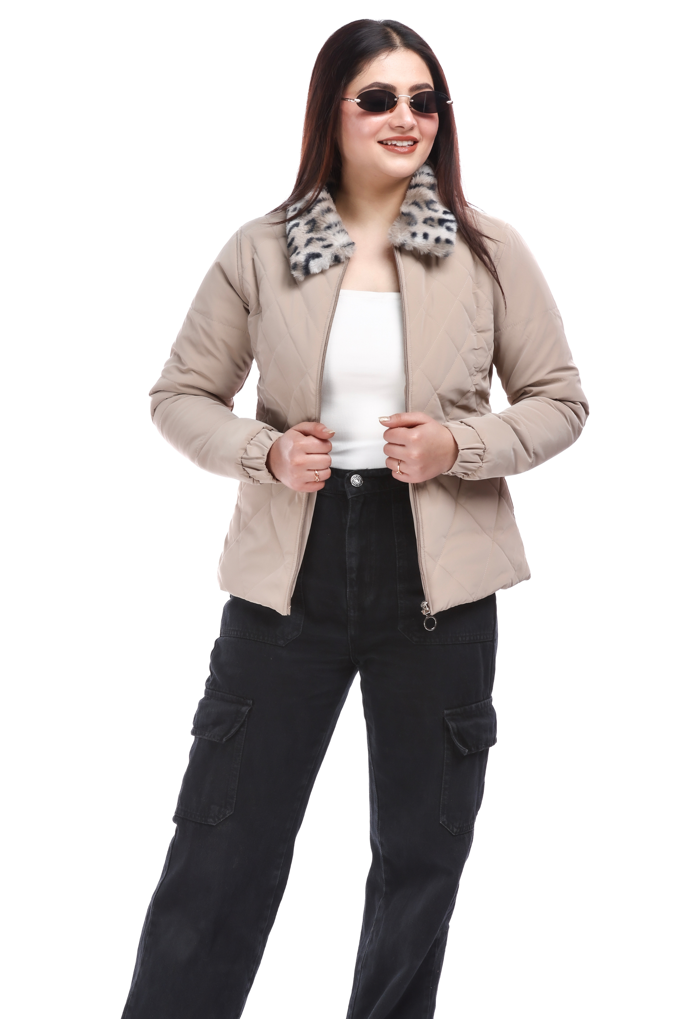 Woman in a cream faux-fur PU jacket styled open over a white top, paired with black cargo pants and sunglasses, posing confidently with both hands holding the jacket edges.