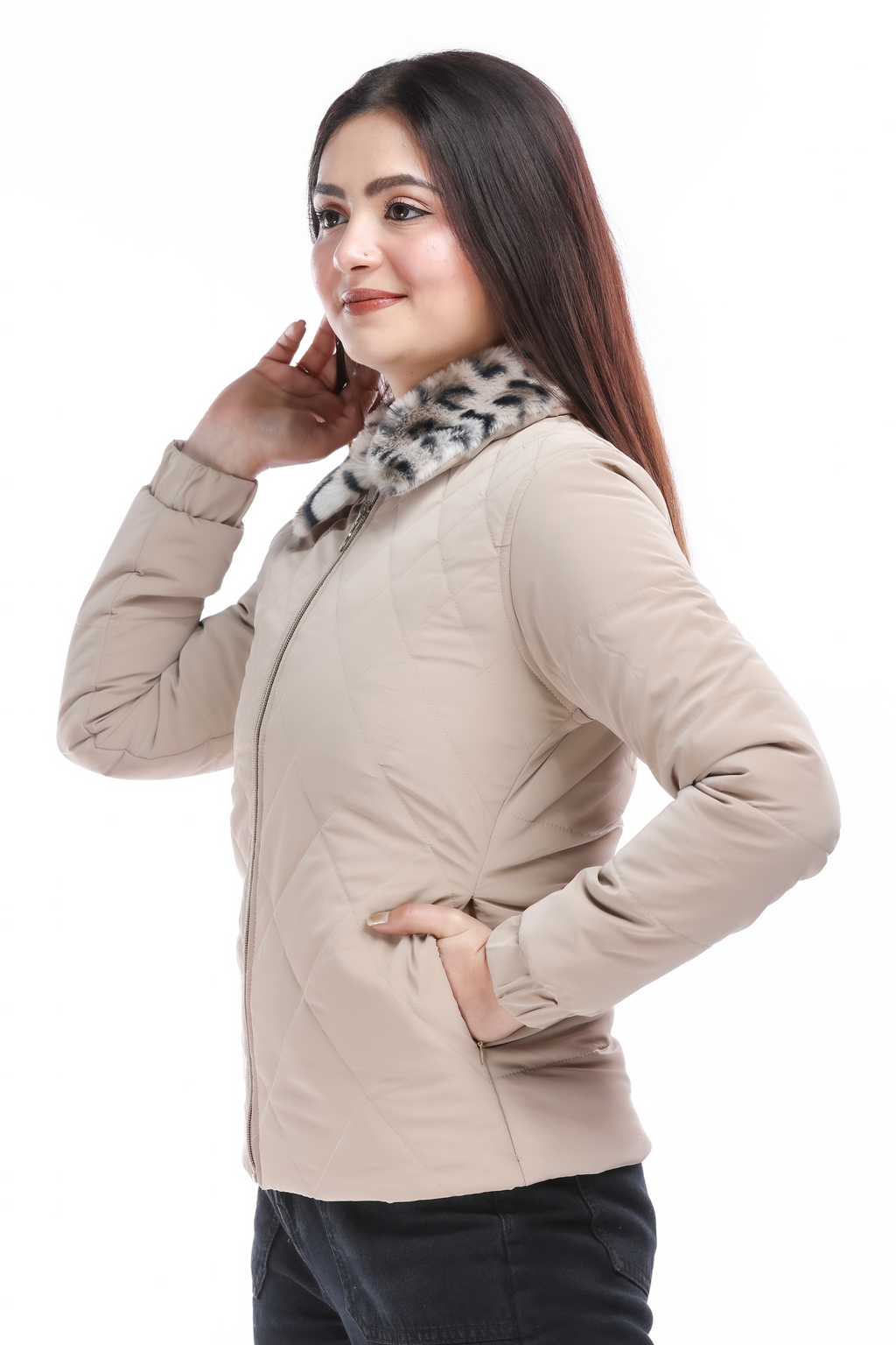 Side view of a woman wearing a cream faux-fur PU jacket with hands in the pockets, showing the quilted texture and animal print collar, smiling while looking away.