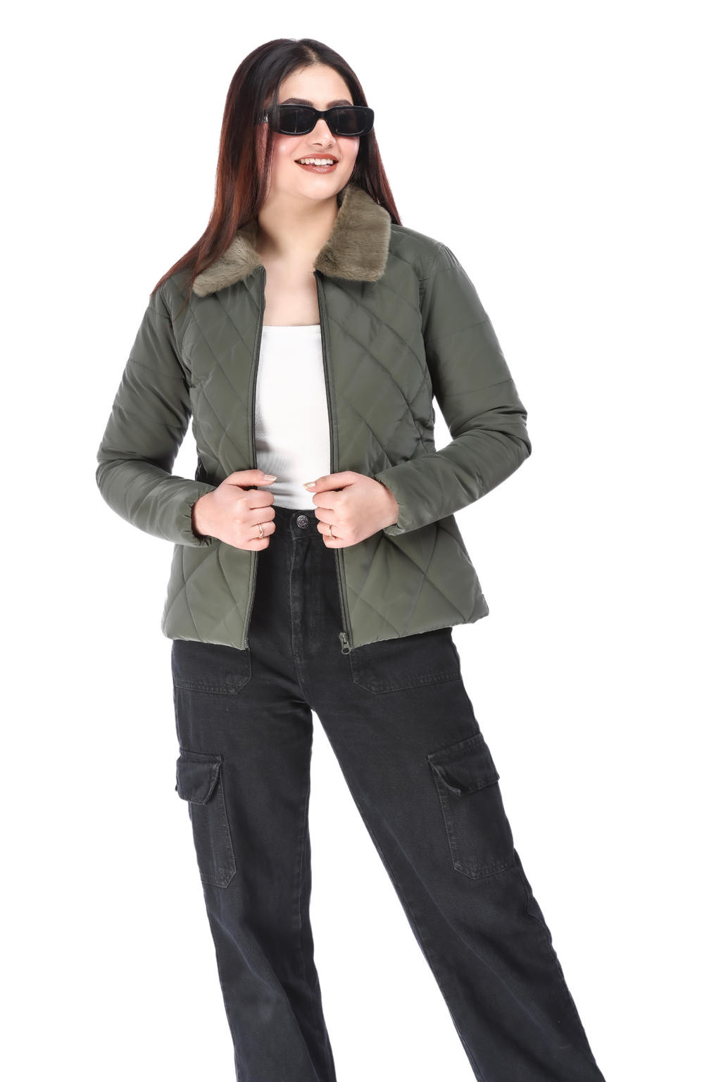 Woman in olive jacket over a white top and black cargo pants, smiling and wearing black sunglasses.