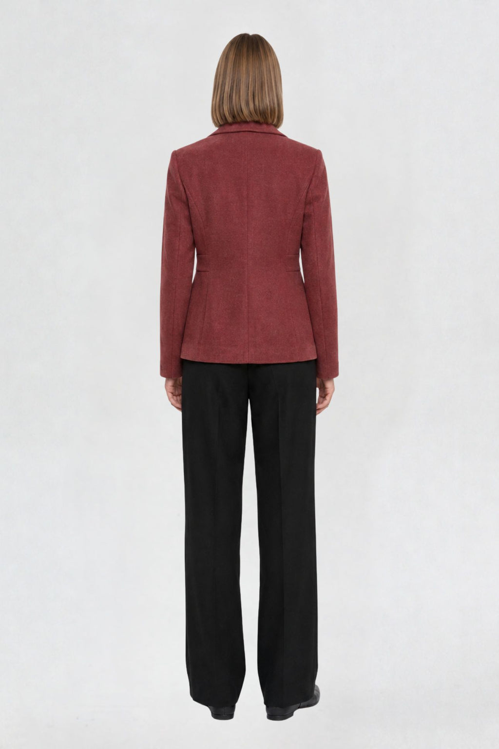 Back view of copper red short blazer coat showing tailored back seams and welt pocket detail