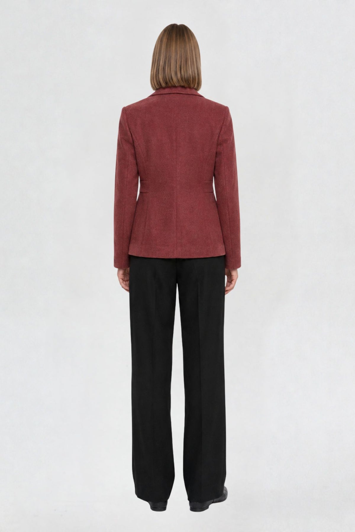 Back view of copper red short blazer coat showing tailored back seams and welt pocket detail