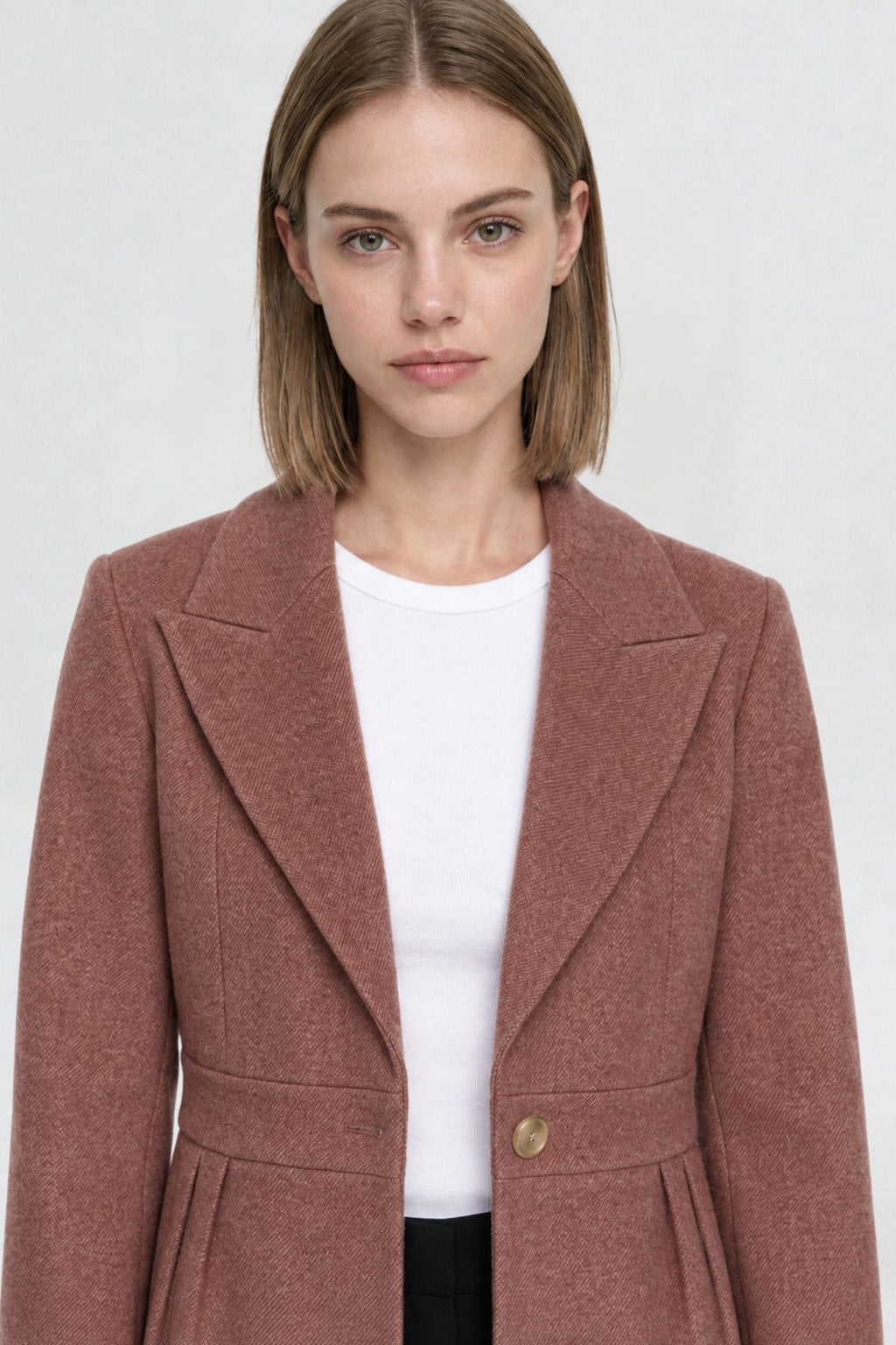 Close-up of dark onion short blazer coat, peaked lapel and gold button detail on textured herringbone-weave fabric