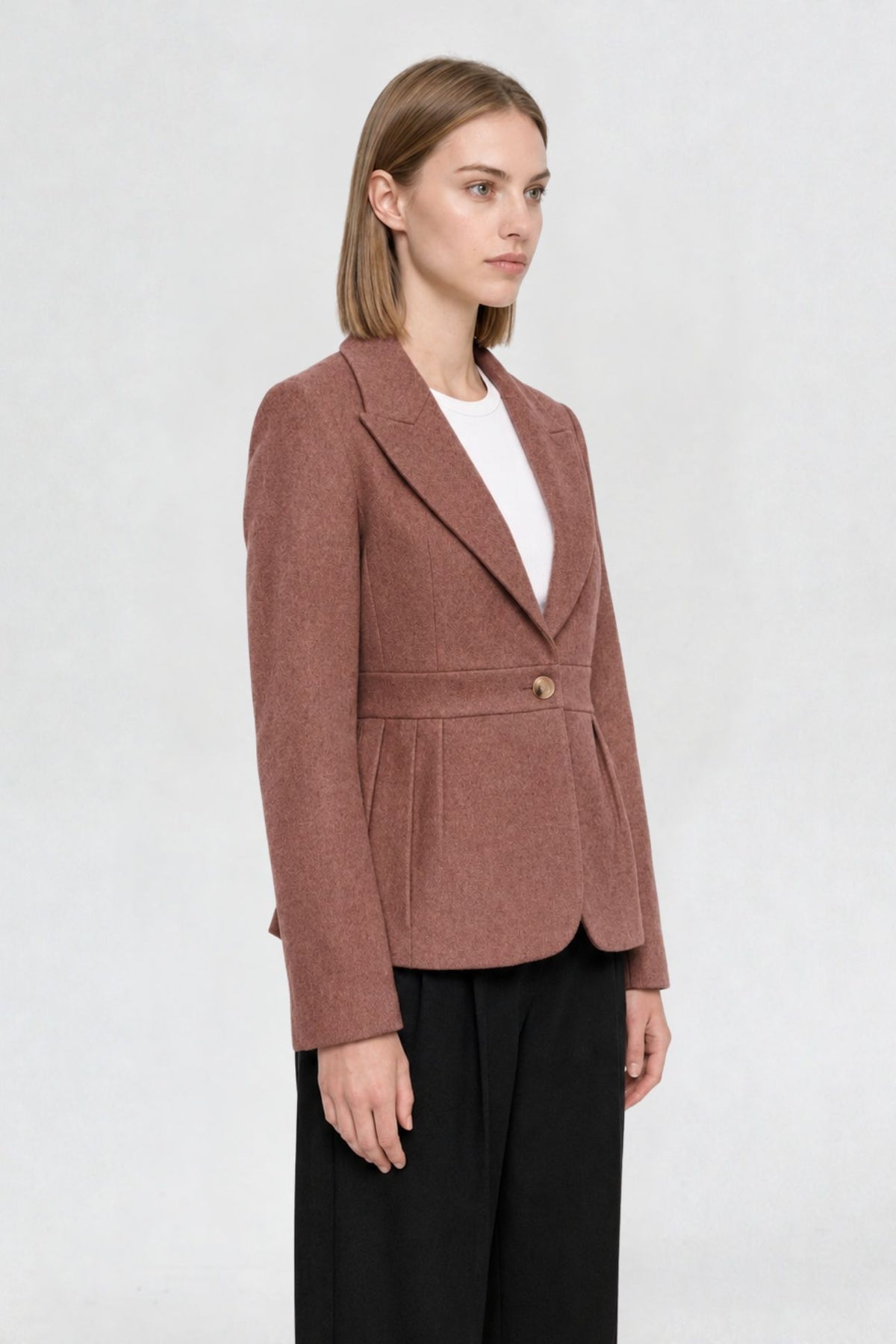 Side view of dark onion short blazer coat showing peaked lapel, single gold button, and pleated waist seam