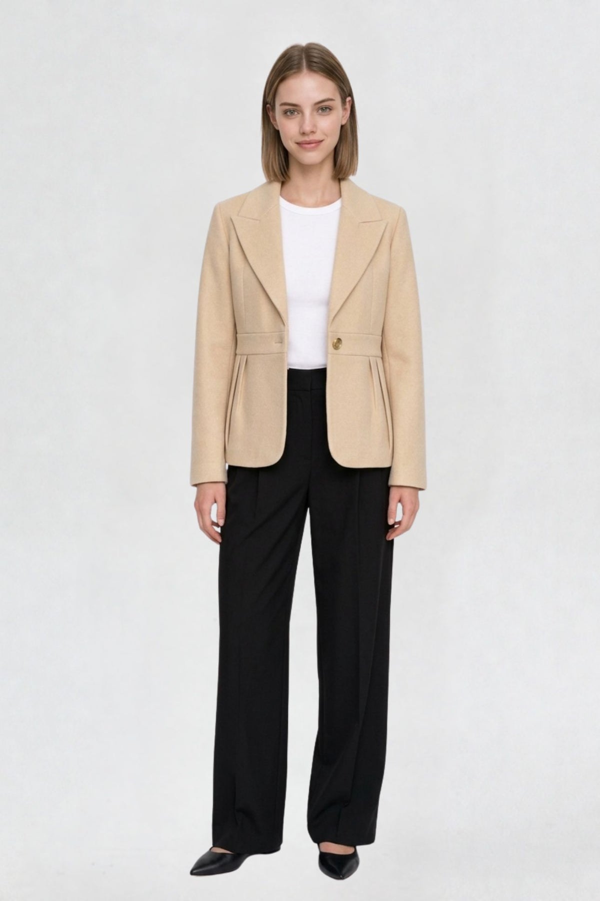 Women's light beige short blazer coat, full front view, single-button closure, pleated peplum hem, styled with black wide-leg trousers