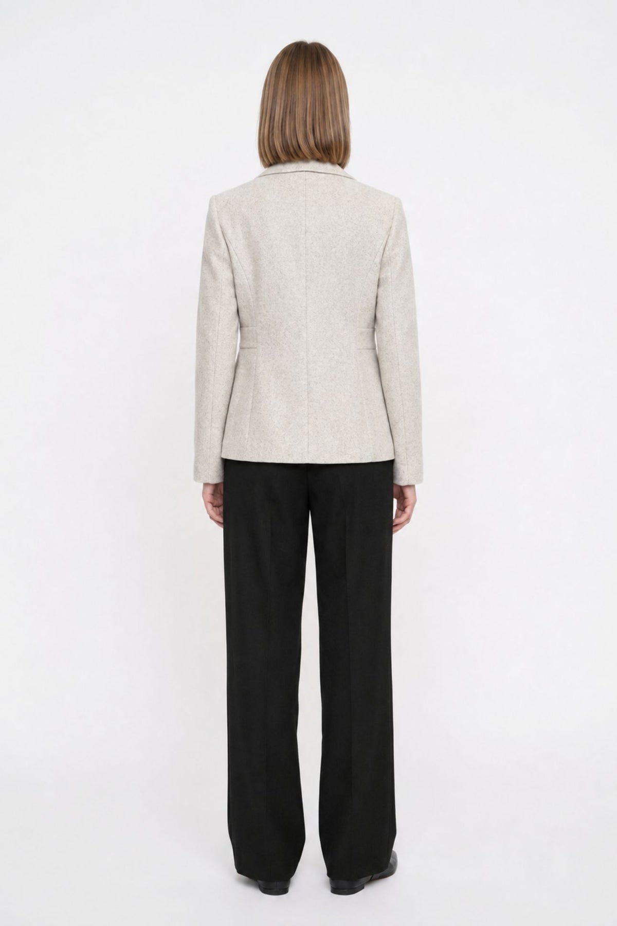 Back view of off white short blazer coat showing tailored back seams and welt pocket detail
