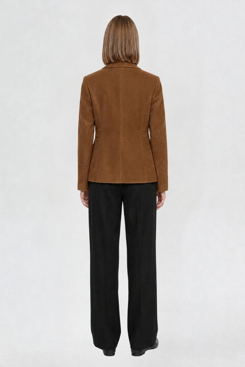 Back view of tan brown short blazer coat showing tailored back seams and welt pocket detail