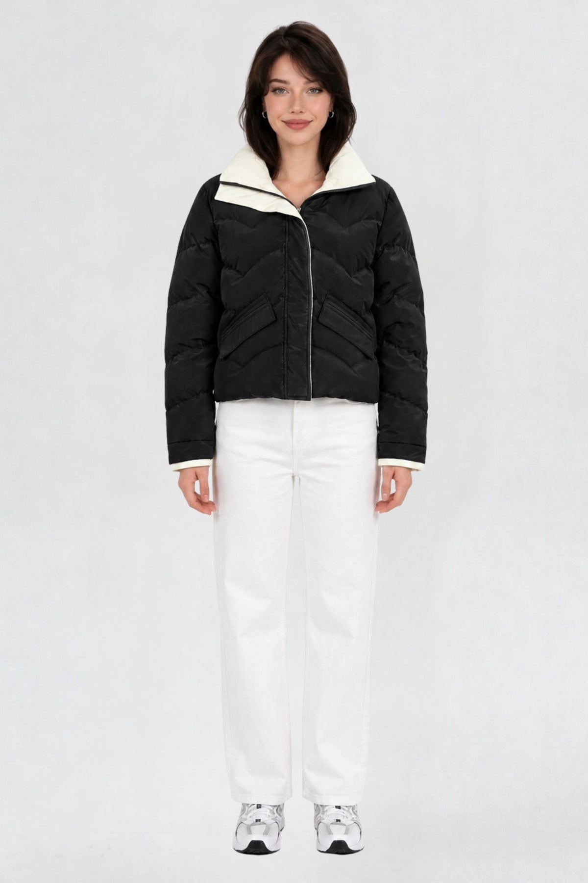 Women's black puffer jacket, full front view, quilted chevron pattern with cream lining, worn with white jeans and sneakers