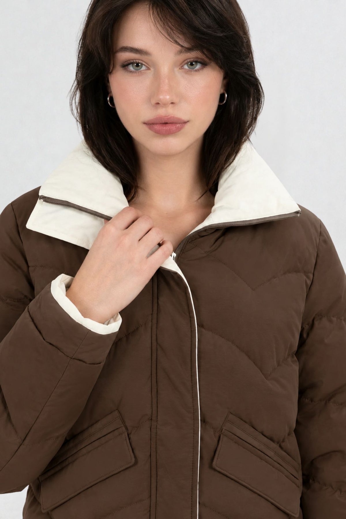 Close-up of coffee brown puffer jacket showing cream contrast zip trim, chevron quilting, and collar detail