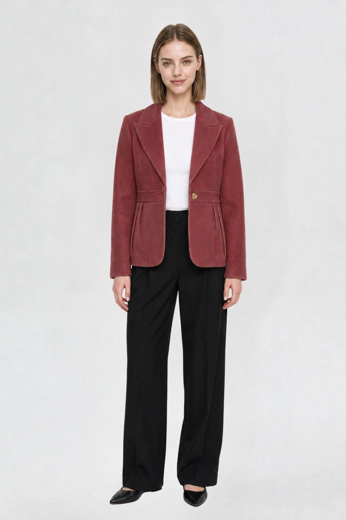 Women's copper red short blazer coat, full front view, single-button closure, pleated peplum hem, styled with black wide-leg trousers