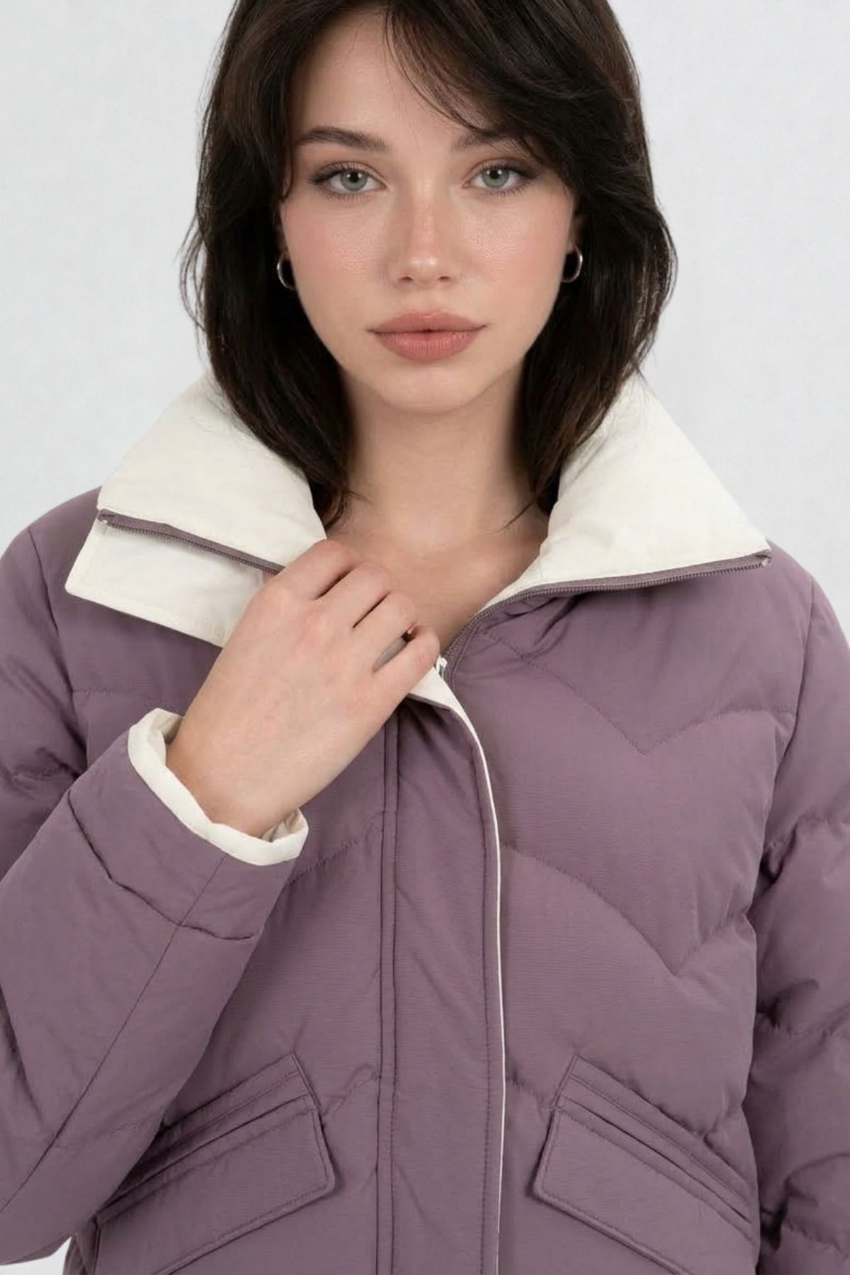 Close-up of mauve purple puffer jacket showing cream contrast zip trim, chevron quilting, and collar detail