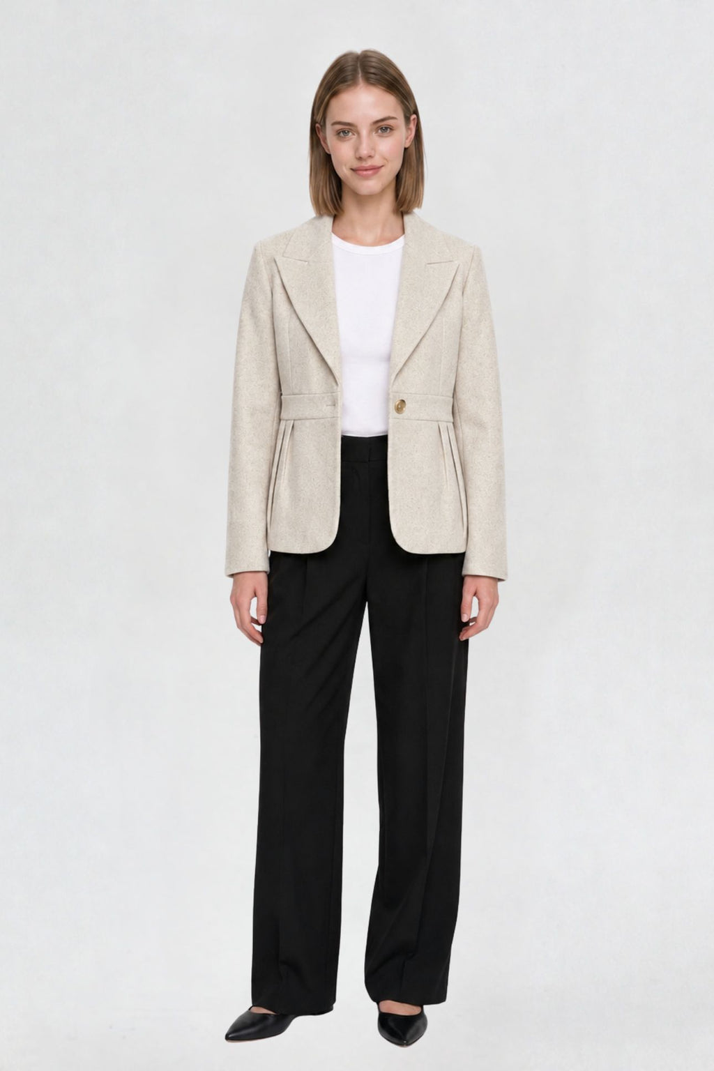 Women's off white short blazer coat, full front view, single-button closure, pleated peplum hem, styled with black wide-leg trousers