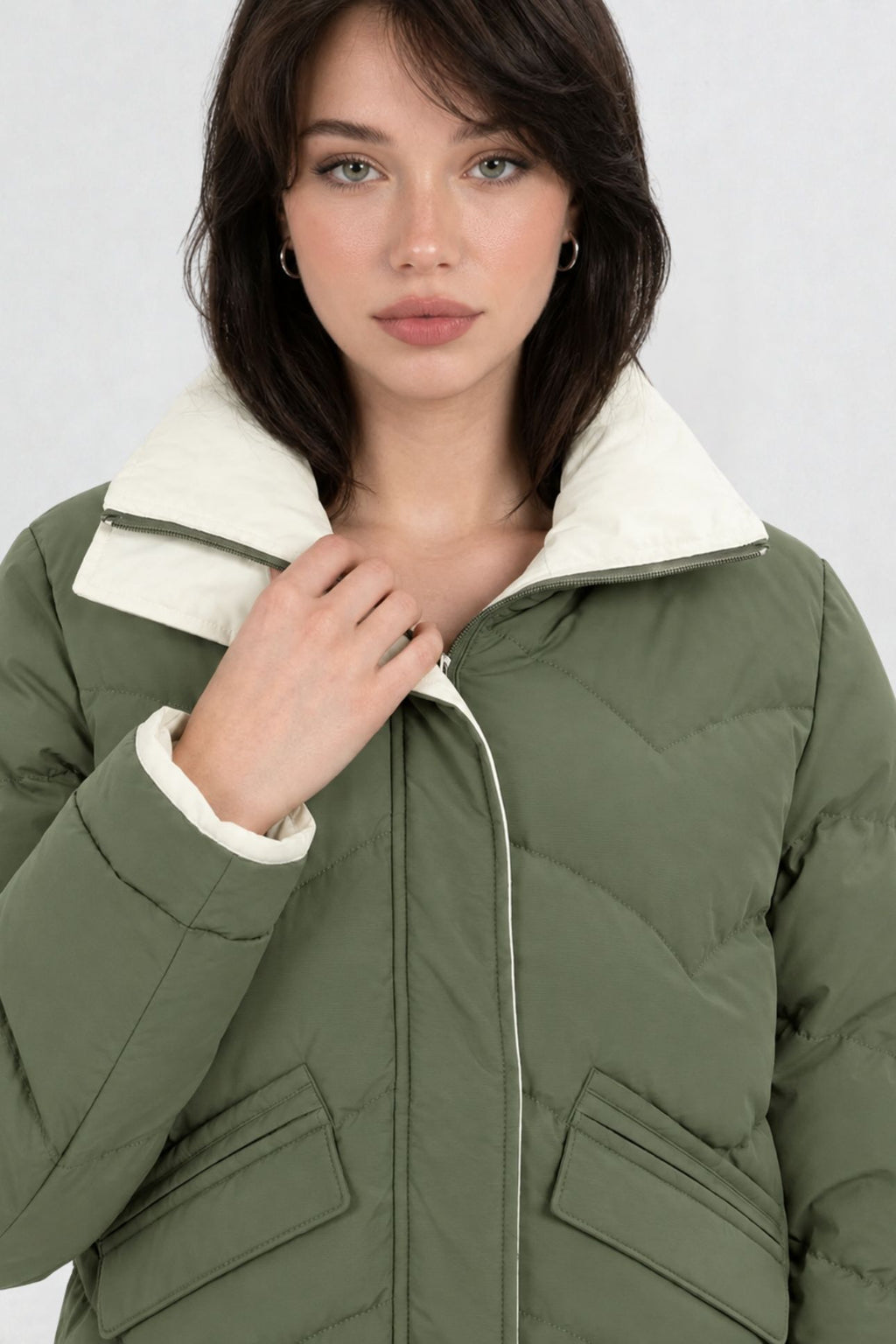 Close-up of pista green puffer jacket showing cream contrast zip trim, chevron quilting, and collar detail