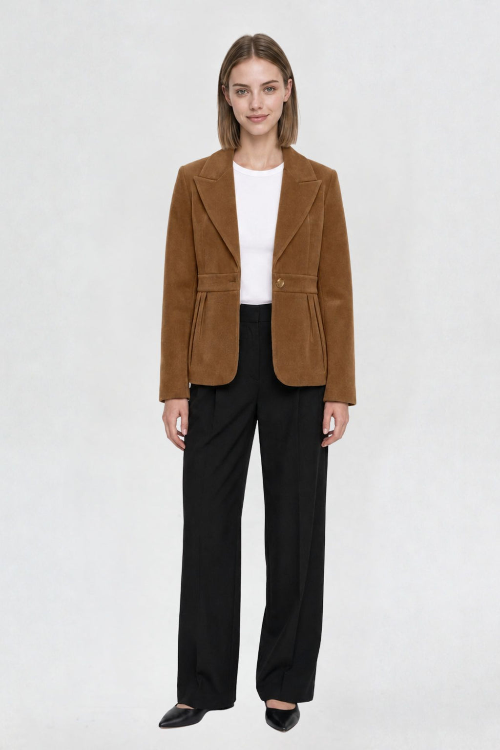 Women's tan brown short blazer coat, full front view, single-button closure, pleated peplum hem, styled with black wide-leg trousers